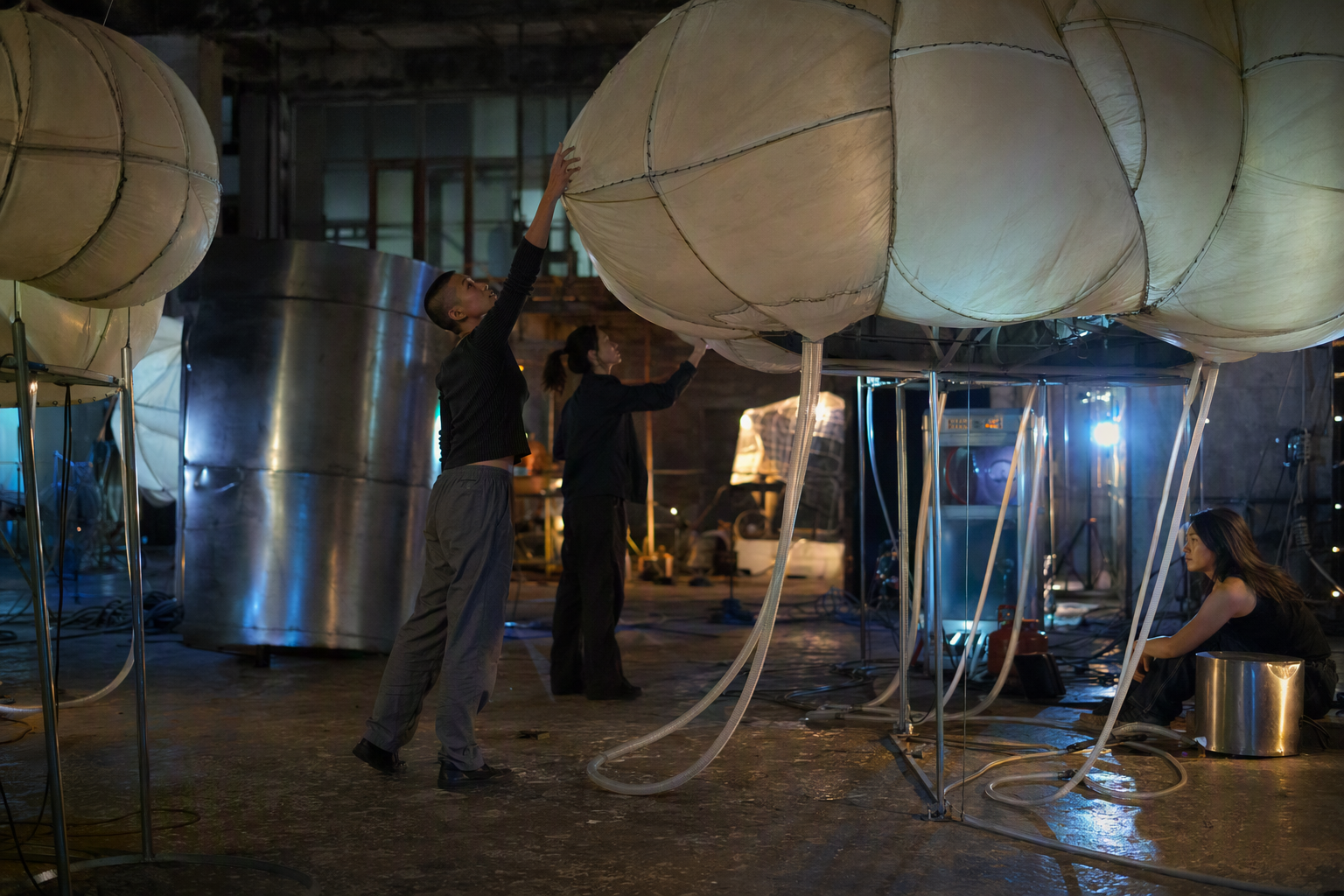 A performer moving among responsive textile sculptures under violet light
