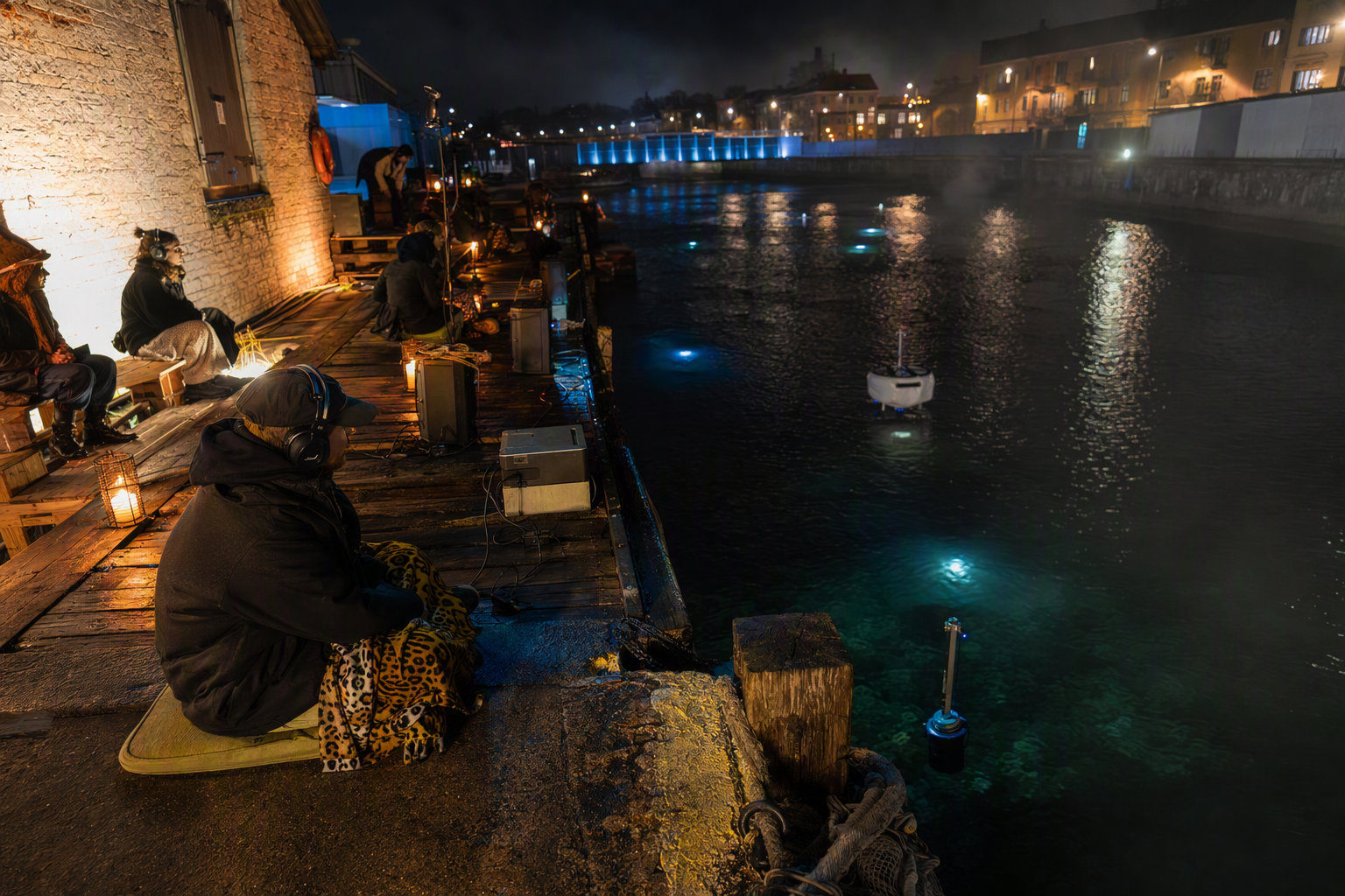 Listeners gathered around hydrophones beside a dark tidal canal
